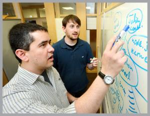 two men standing and looking attentively at a whiteboard 