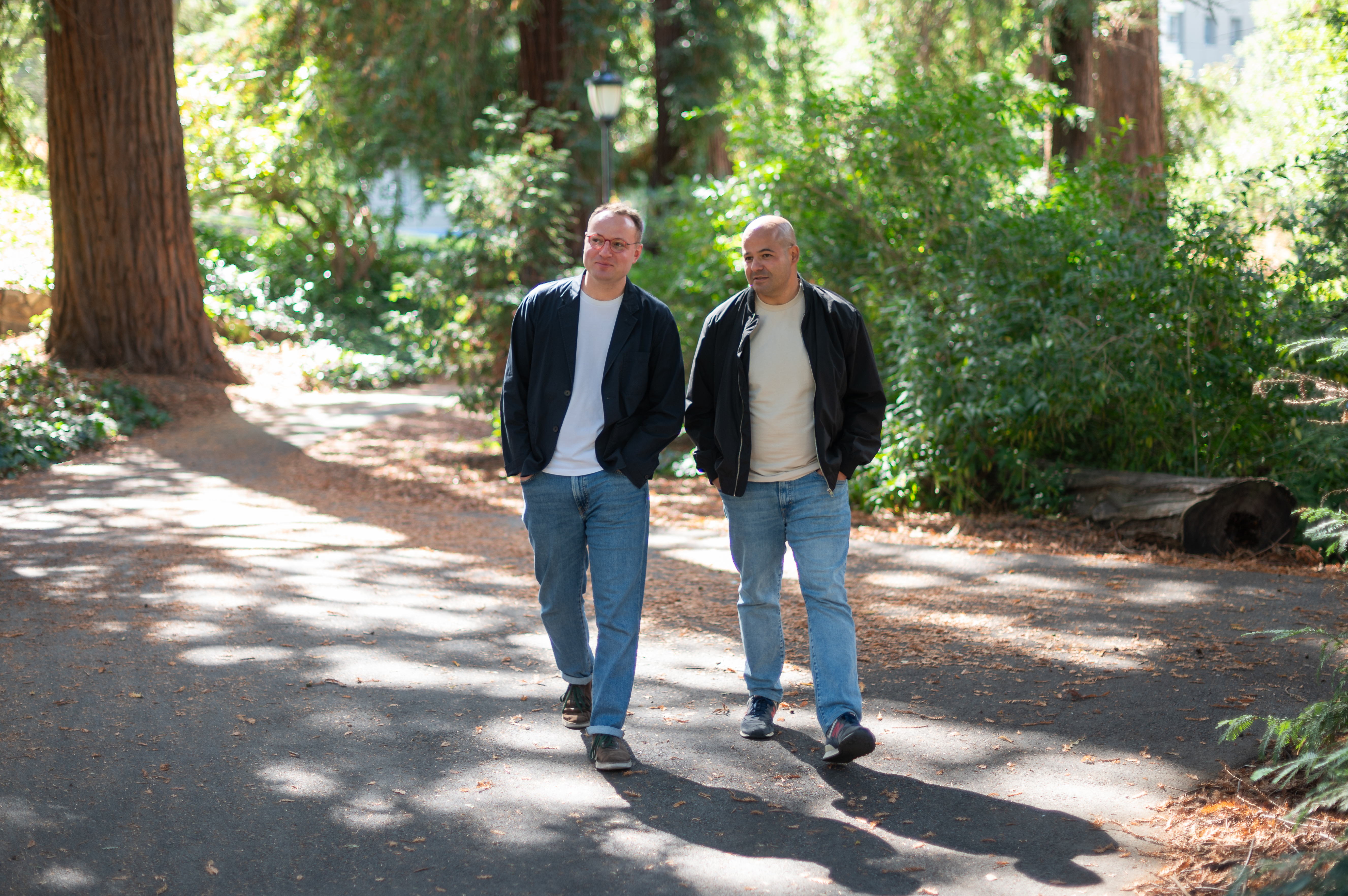 two men walking together in a forest background