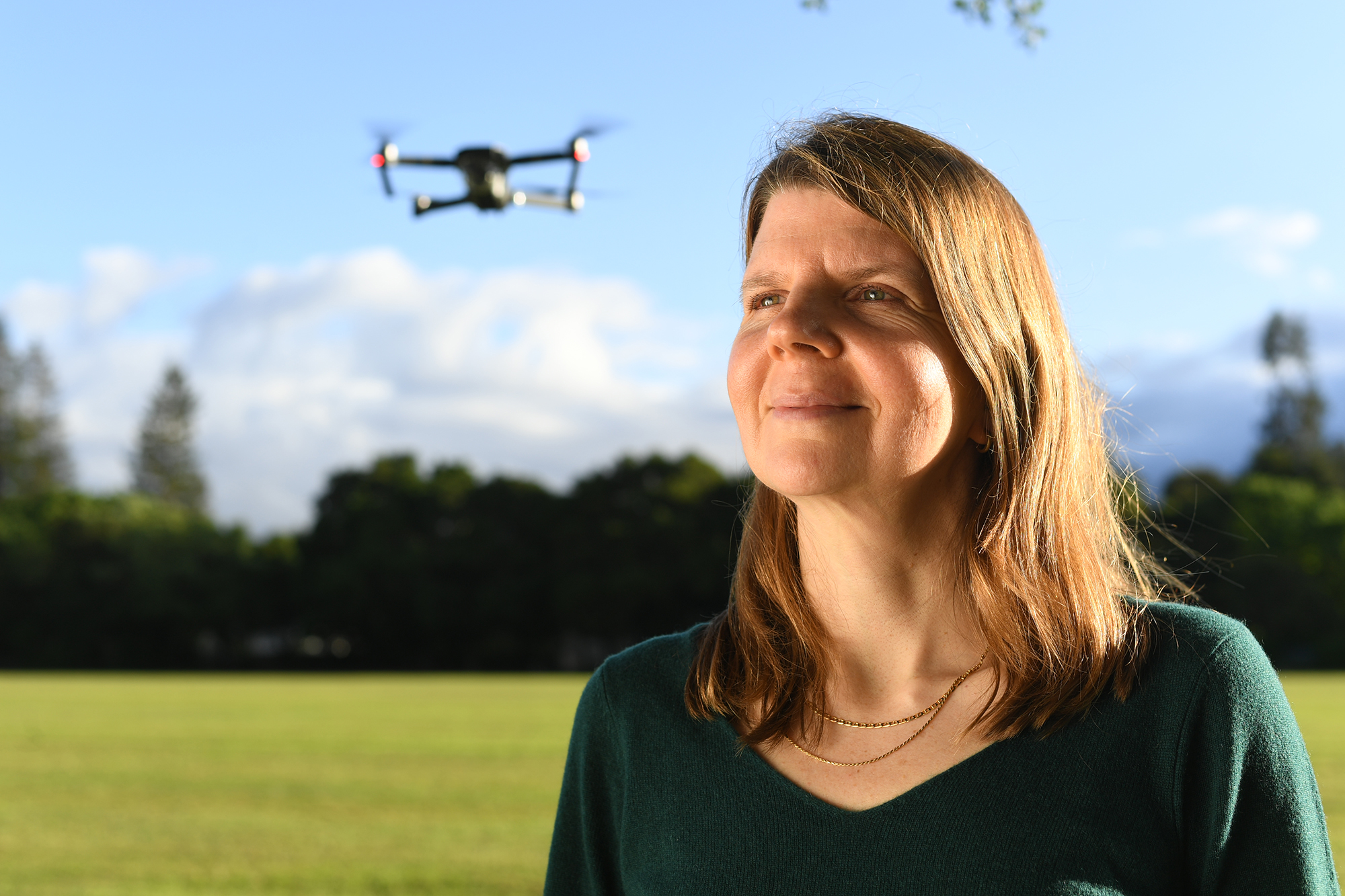 woman looking off into distance with drone behind her