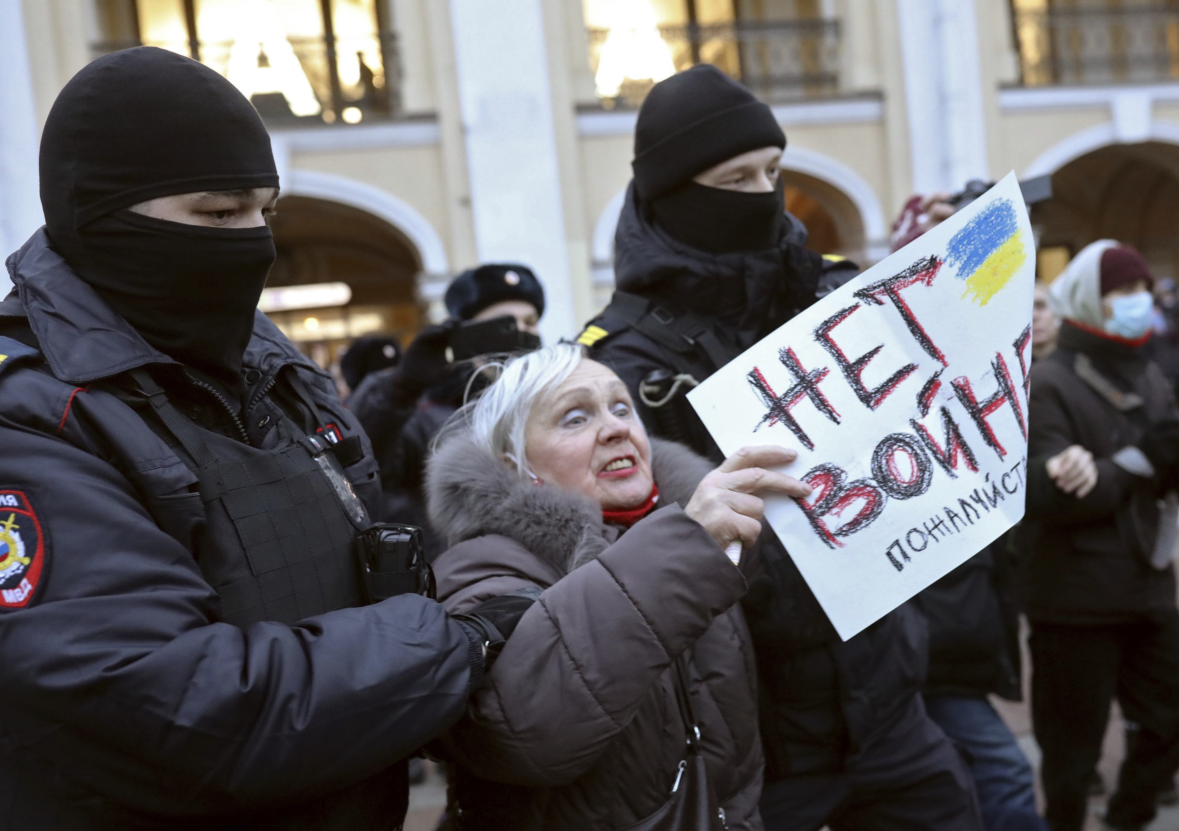an older woman with white hair holding a sign that says in Russian 