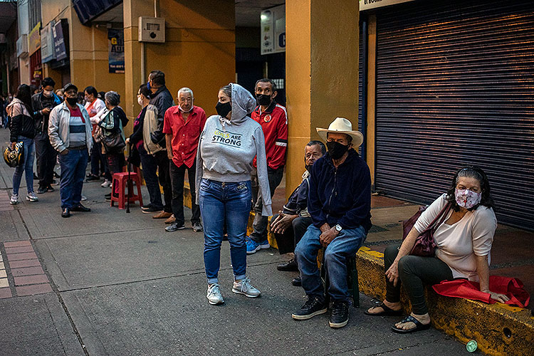 people of different ages wait in line for pandemic-relief aid in Medillin, Colombia