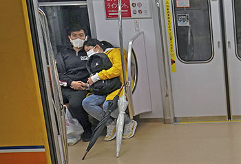 A masked couple in Tokyo rides the subway