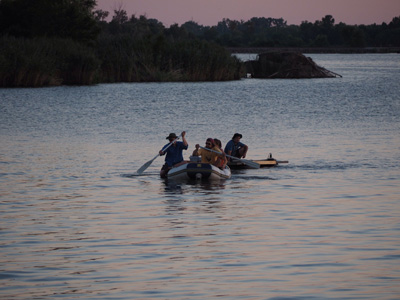 people in canoe on water at dusk