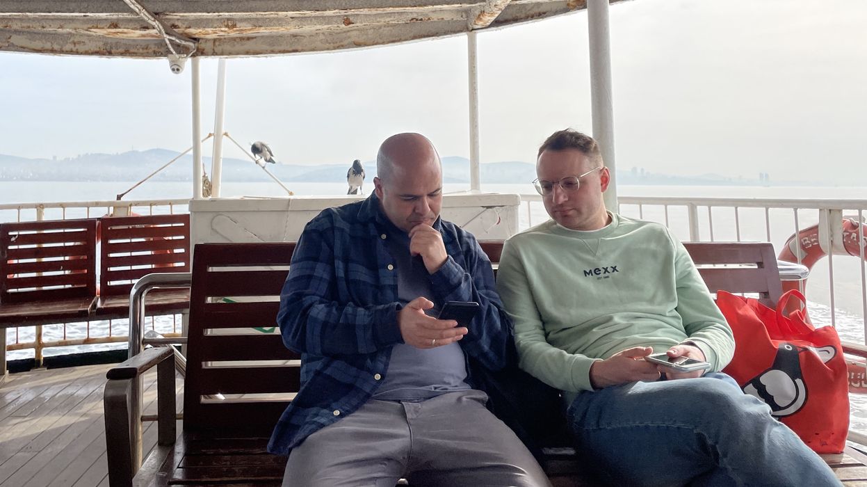 two men sitting on boat looking at their phones