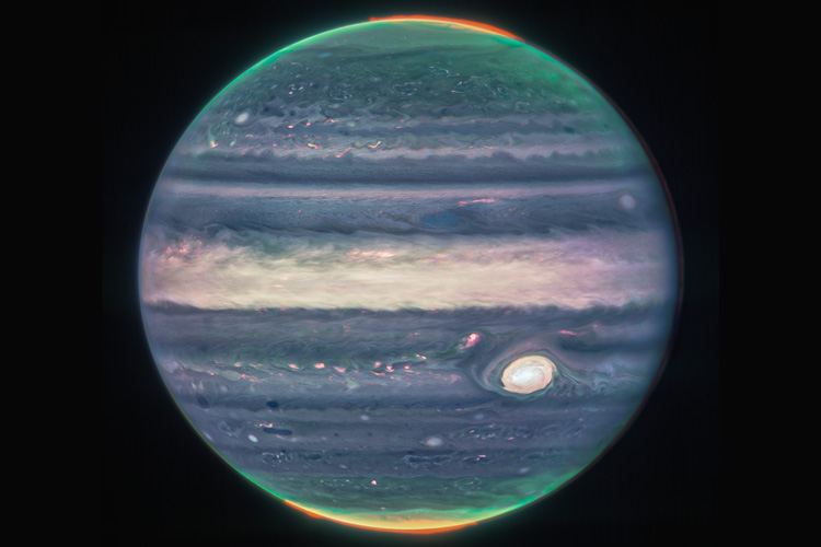 blue and green orb of Jupiter, with a fringe of orange-red auroras at both poles