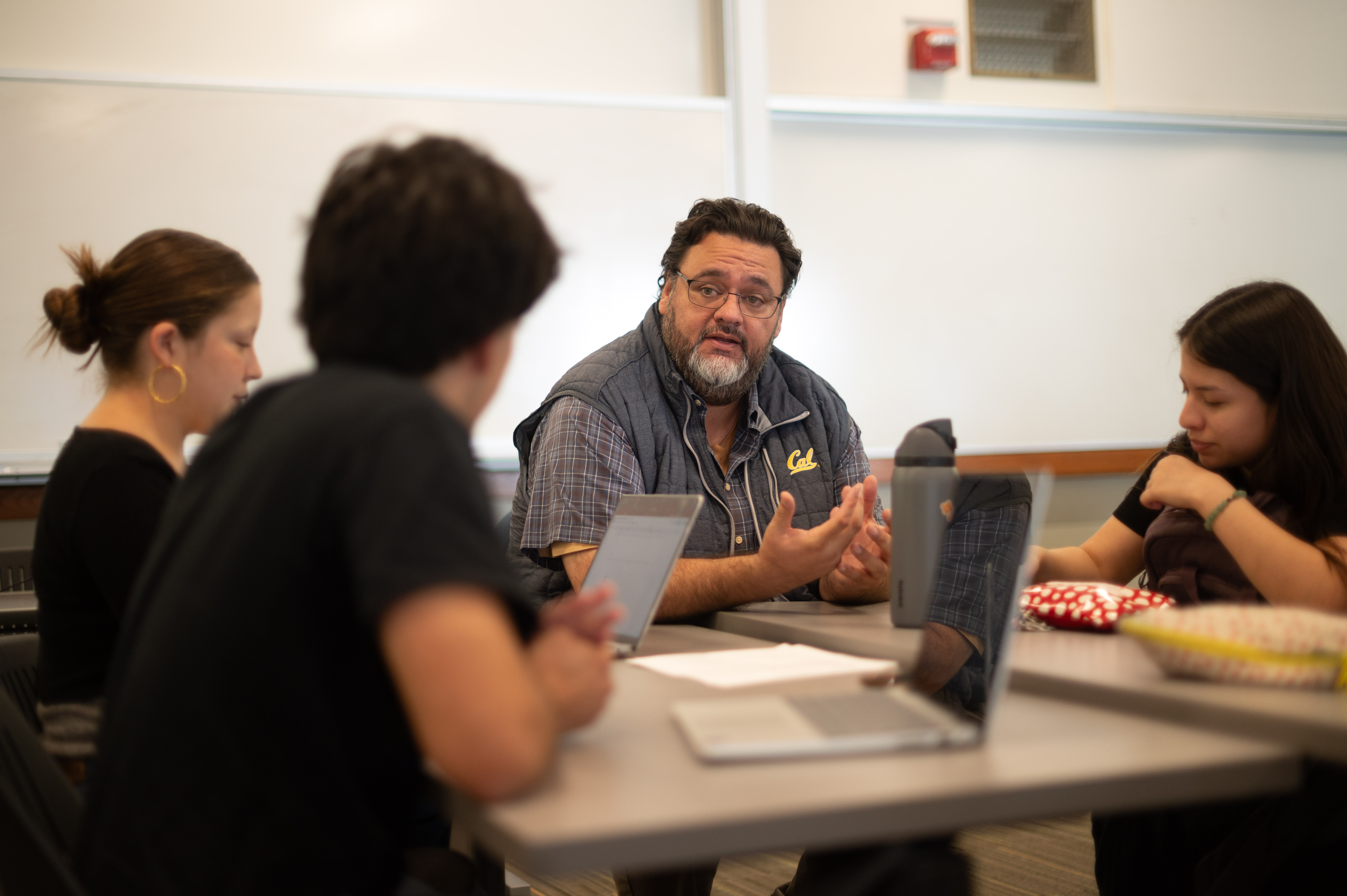 Pablo Gonzalez sits at a table with students talking.