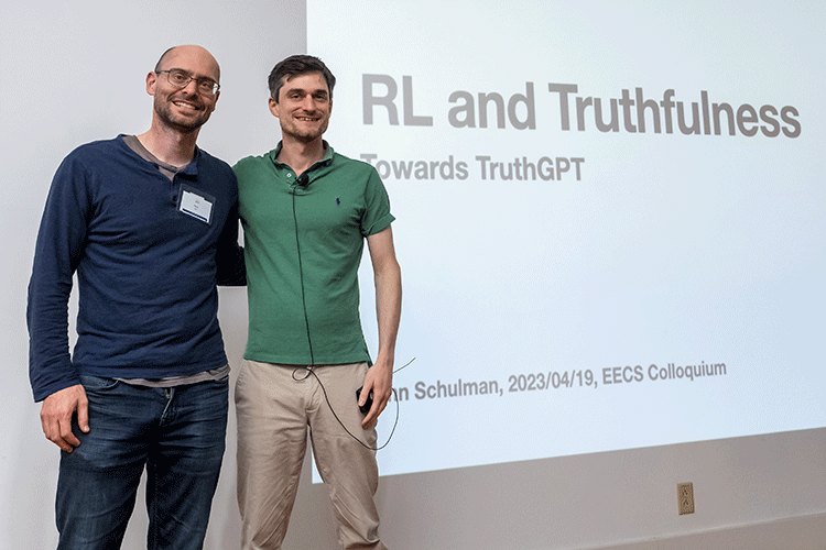 John Schulman and Pieter Abbeel pose on a stage in front of a projection that reads “RL and truthfulness”