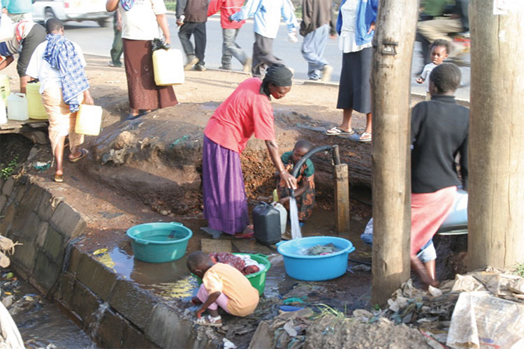 A photo of a woman in Nairobi filling a bucket with water