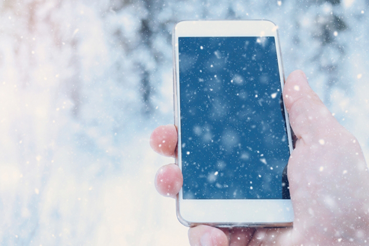 A hand holding an iPhone in snowy weather