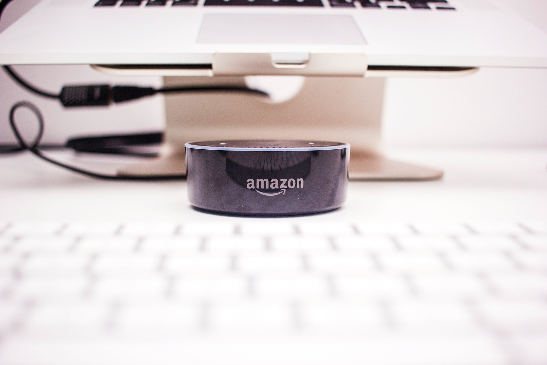An Amazon Echo Dot on a desk next to an Apple laptop and keyboard, showing how a handful of technology companies have increasingly shaped daily life