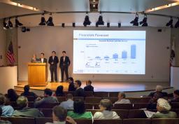 Three researchers present to an audience in a lecture hall.