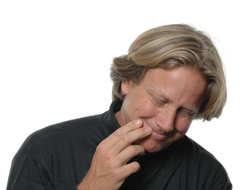 Dacher Keltner looks down, smiling slightly, and puts his hand to his chin.