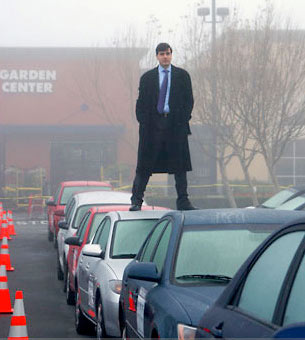 A man stands on top of a car in traffic.