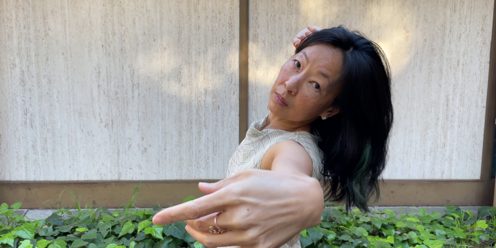 headshot of Asian woman gesturing toward the camera