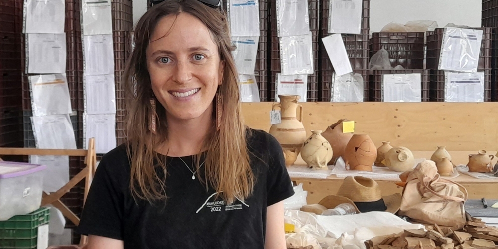 Photo of Grace Erny in front of table with archaeological ceramics