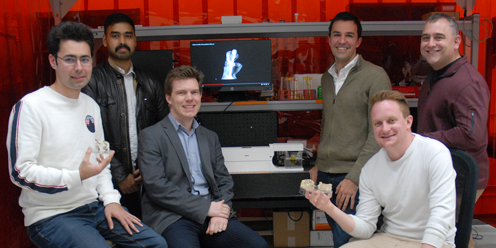 Hayden Taylor (third from left) with group members and collaborators holding components produced by computed axial lithography