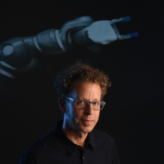 Ken Goldberg in front of a projection of robotic arm
