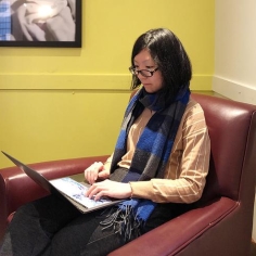 Xueyin (Snow) Zhang sitting in a chair working on laptop