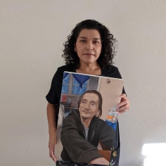 Luanne Redeye holding a portrait of a man in a black sweatshirt