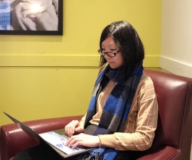 Xueyin (Snow) Zhang sitting in a chair working on laptop