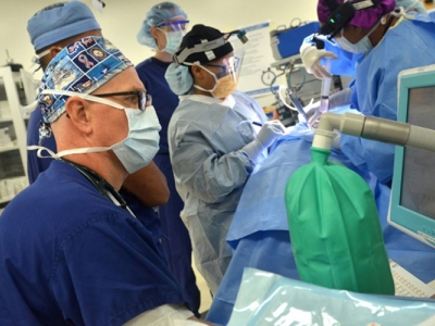 Doctors and nurses wearing masks gather in an operating room