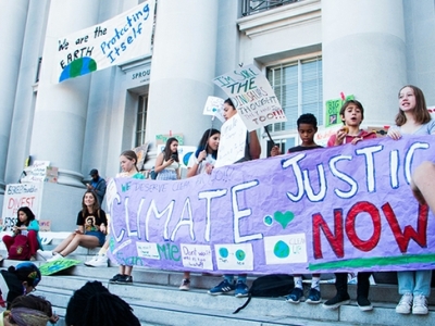 Activist demonstrating with a banner that reads "Climate Justine Now"