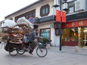 man riding bike in China carrying cardboard