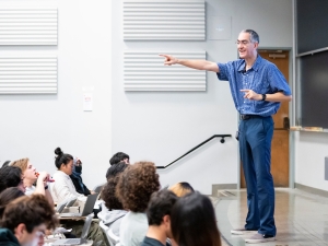 Dan Garcia lectures in front of a classroom with seated students in front of him. Several students have their hands raised.