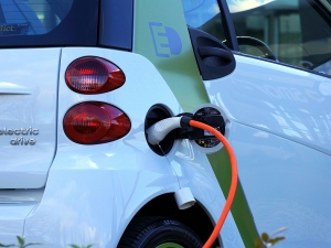 a charging cord inserted into the port of a white electric drive car