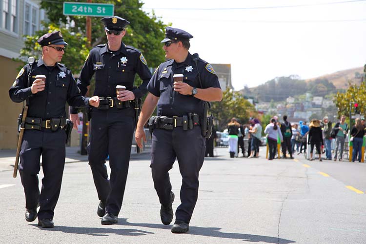 three police officers walk on a street in san francisco