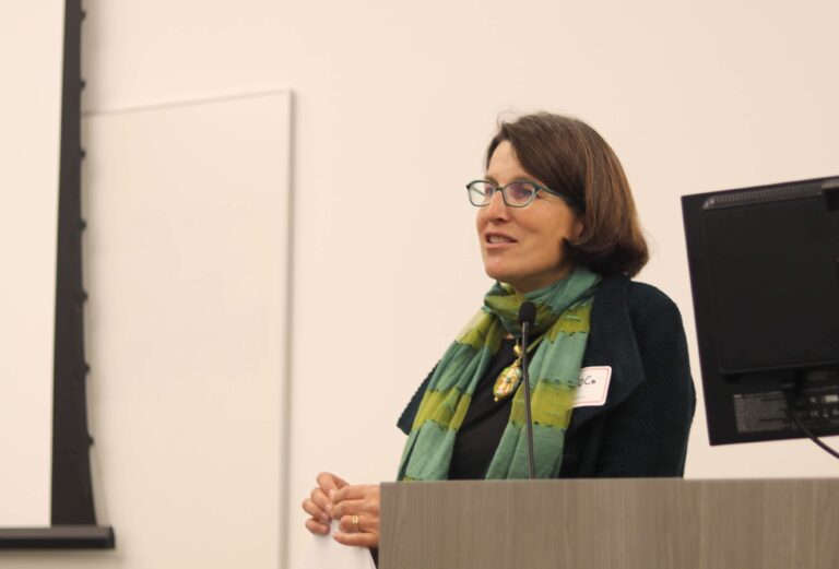 Coco Auerswald speaking at a podium during a 2019 event.