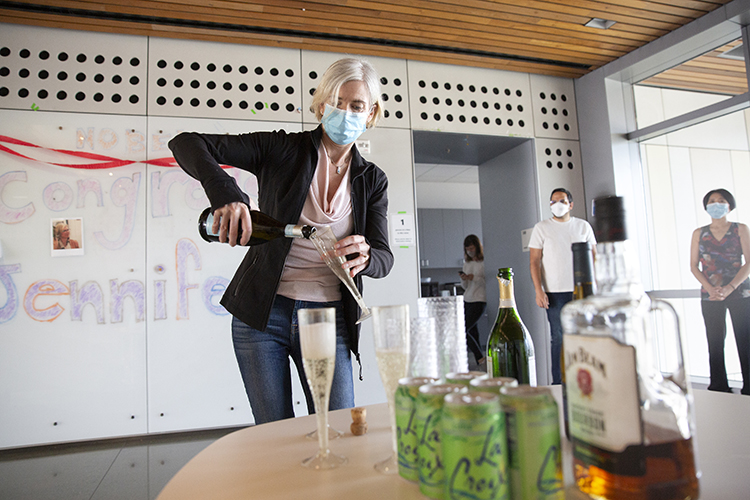 Jennifer Doudna pours champagne while wearing a mask