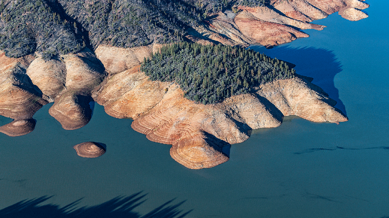 An aerial photo of Shasta Lake. The water level is low and the &quot;bathtub ring&quot; left by higher water levels is clearly visible.