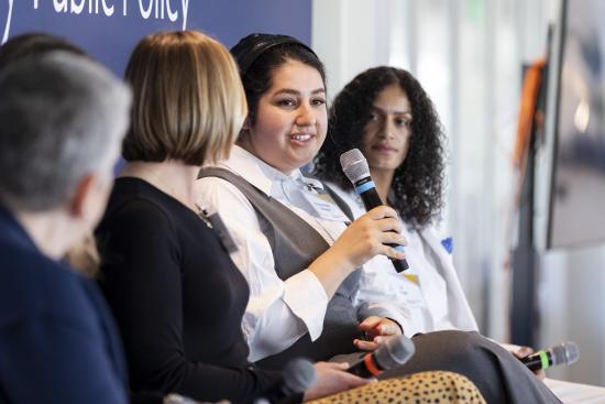 image of a woman holding a microphone giving a talk on a panel