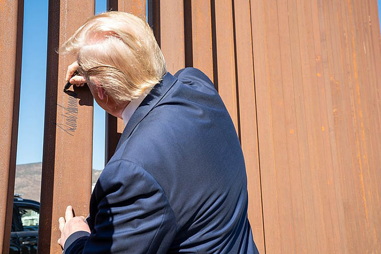 trump, with his back to the camera, signs a section of border wall