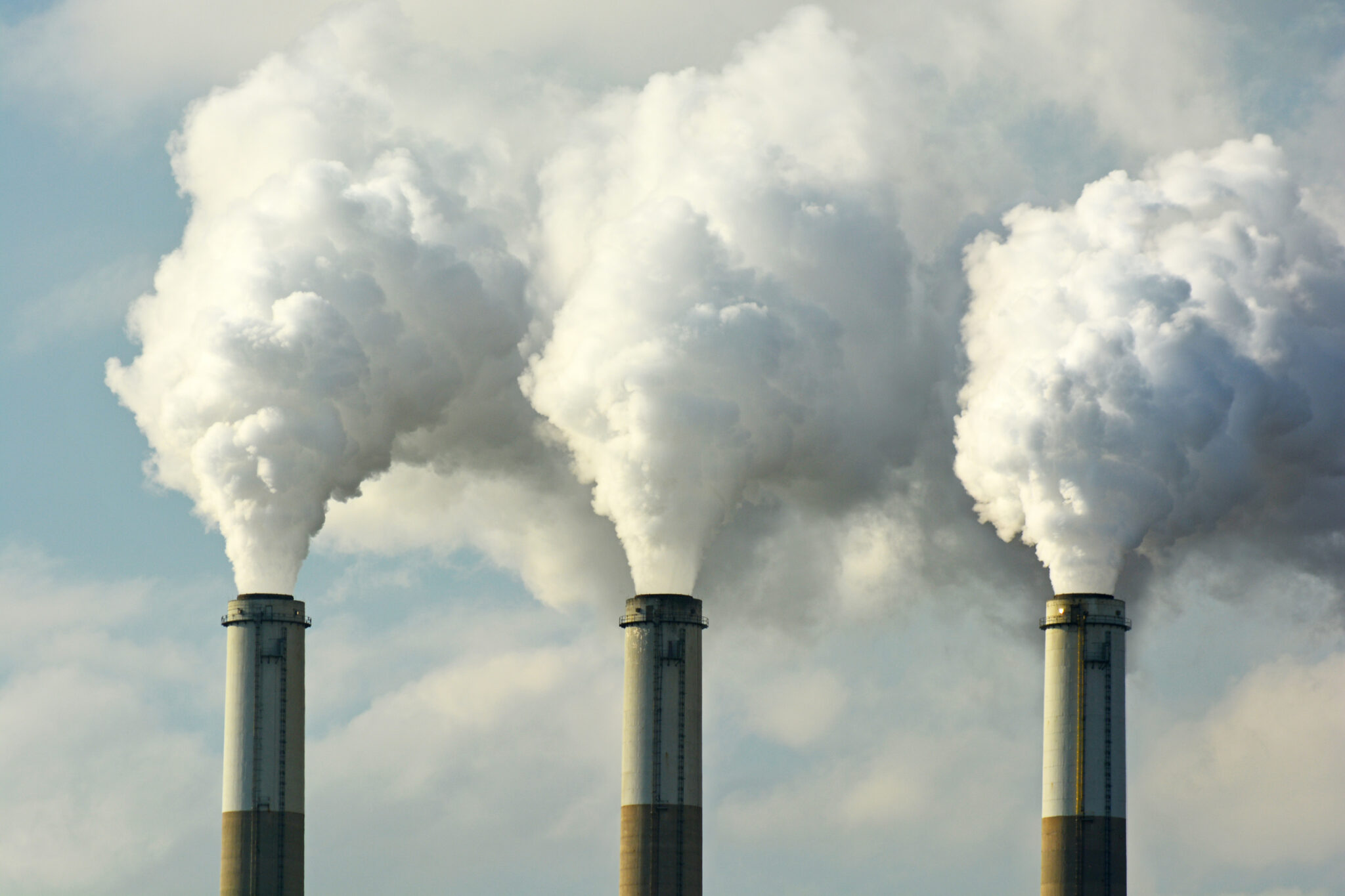 image of three industrial chimneys pumping out clouds of smoke