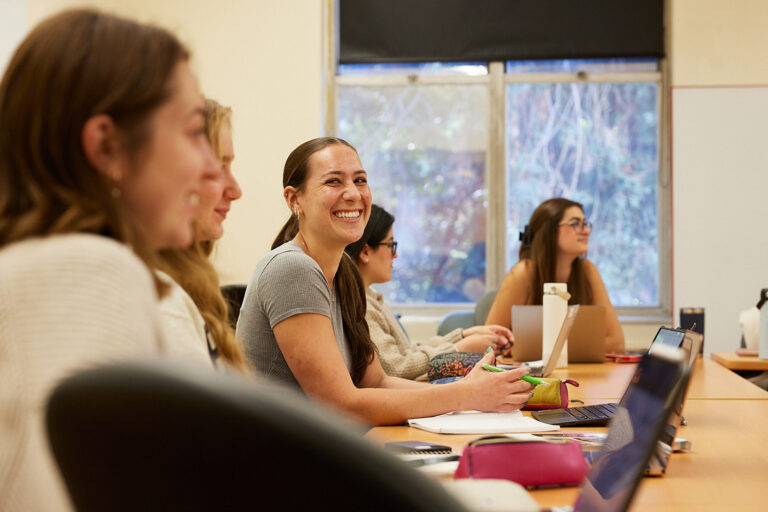 Students in Annamaria Bellezza's class sit around tables and are enjoying studying Elena Ferrante's work. One student smiles broadly.