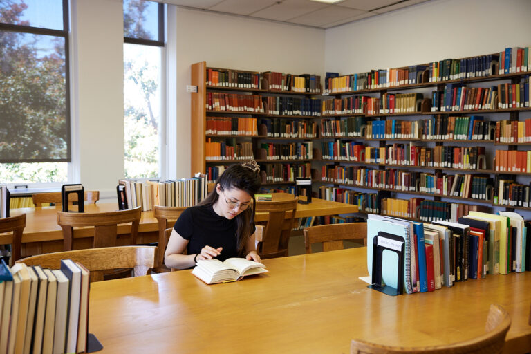 image of woman reading a book at the library