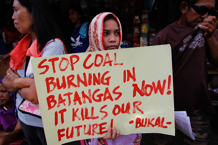 Woman hold a protest sign against coal mining.