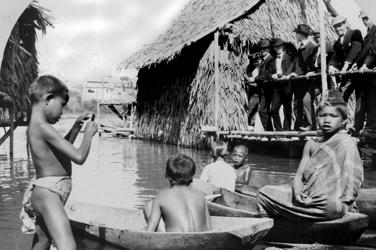Philippine children playing in the water being watched by white men