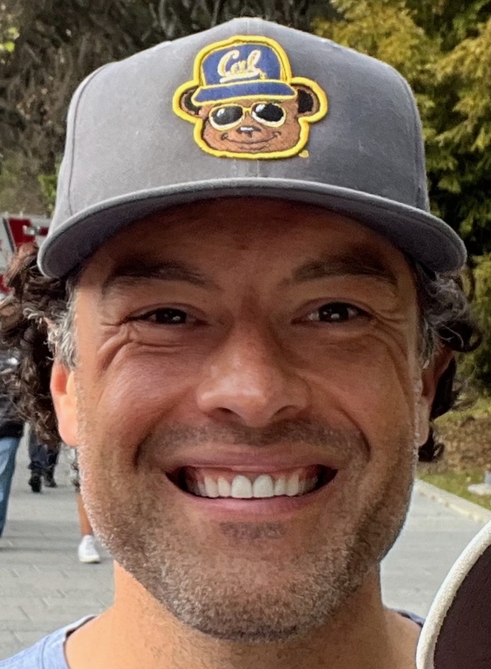 headshot of man wearing a hat smiling 