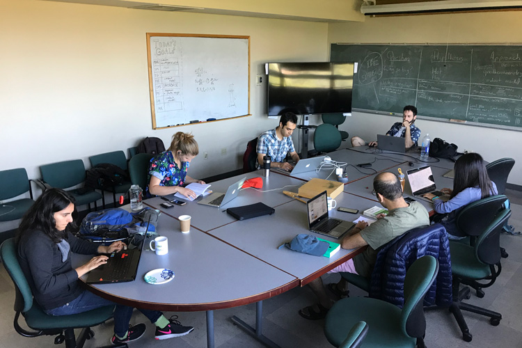 6 members of the Steamboat Geyser team arrayed around a table with their computers