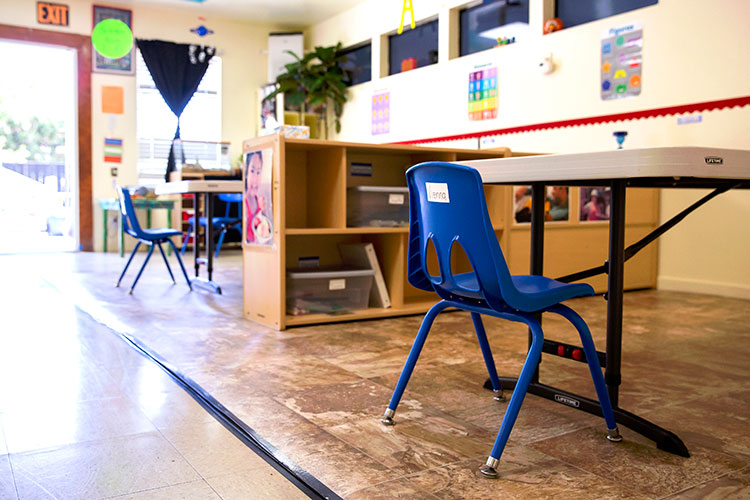a small, empty blue chair at a table in an empty early child education center.