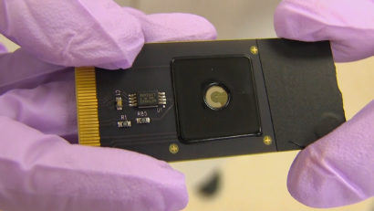 A photo of gloved hands holding an electronic chip