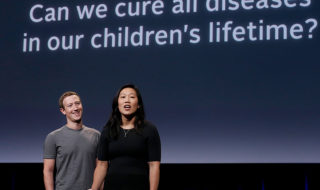 Mark Zuckerberg and Priscilla Chan stand in front of a screen on a stage
