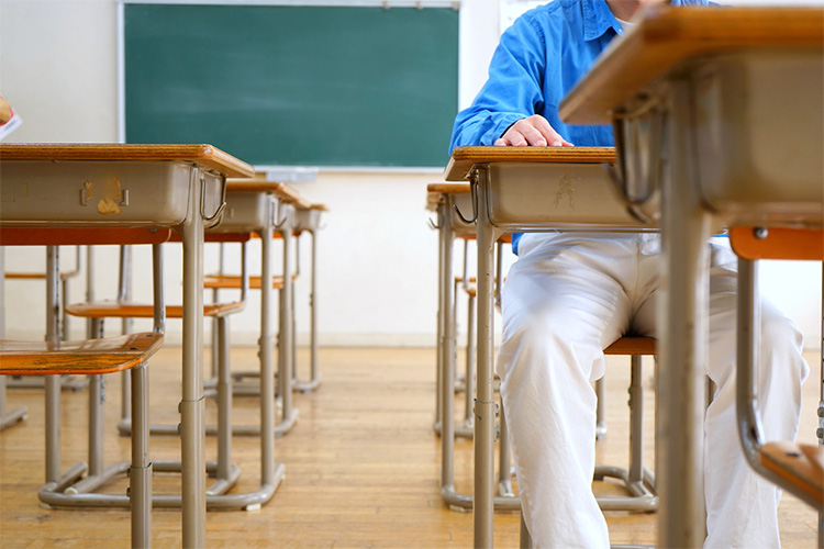 Person sitting at school desk in a row of school desks