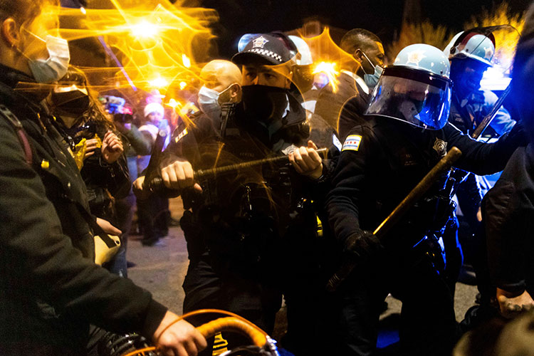 Chicago police in riot gear form a threatening line against protesters following the police killing of Adam Toledo