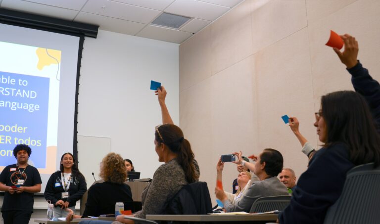 People raise red or blue cards during a high school student-led activity on the Berkeley campus