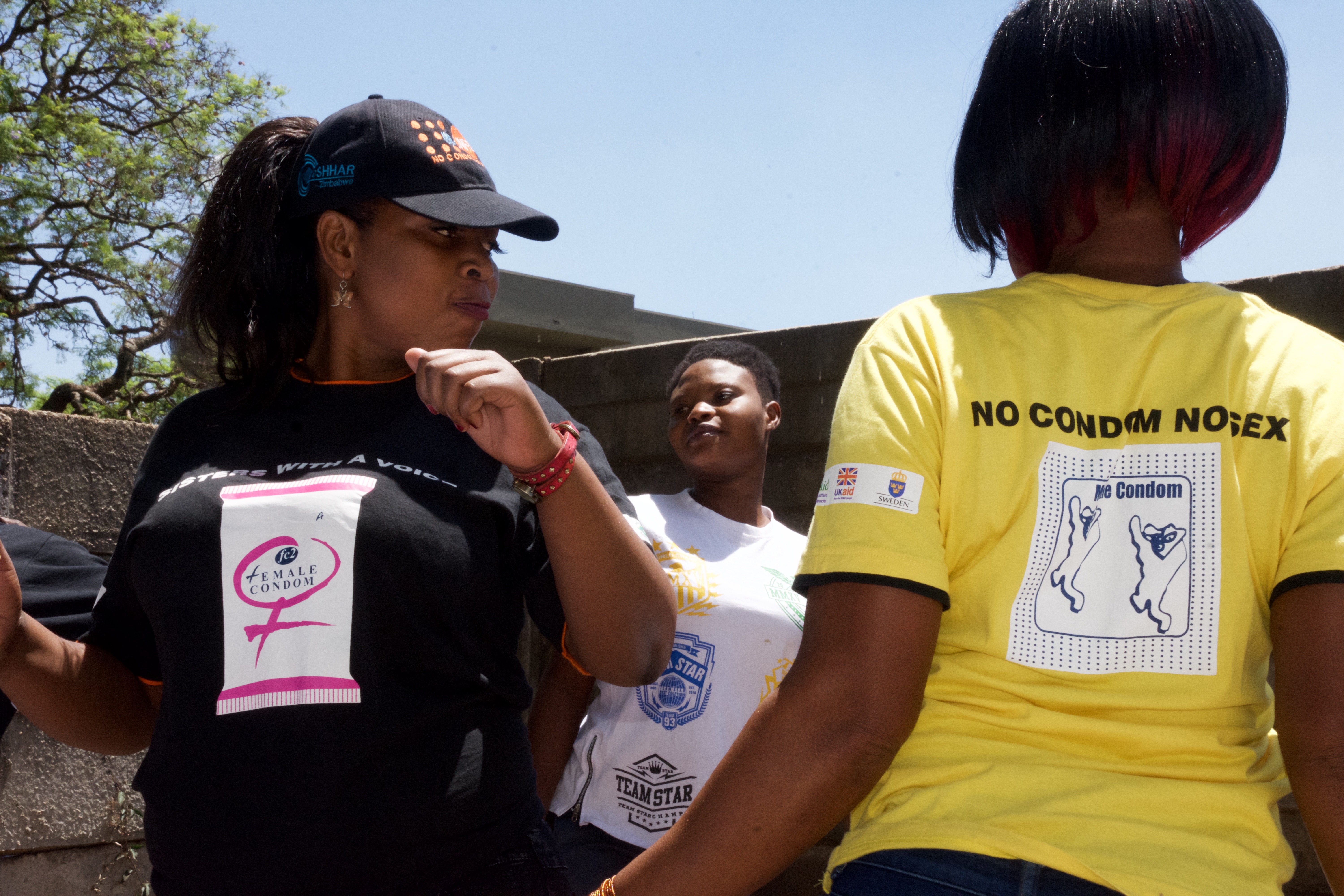 3 women wearing t-shirts that say 'female condom' and 'no condom no sex'