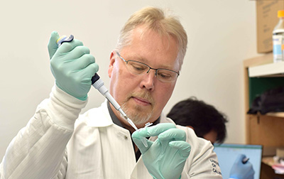 Anders Naar holds a pipette and test tub in a lab